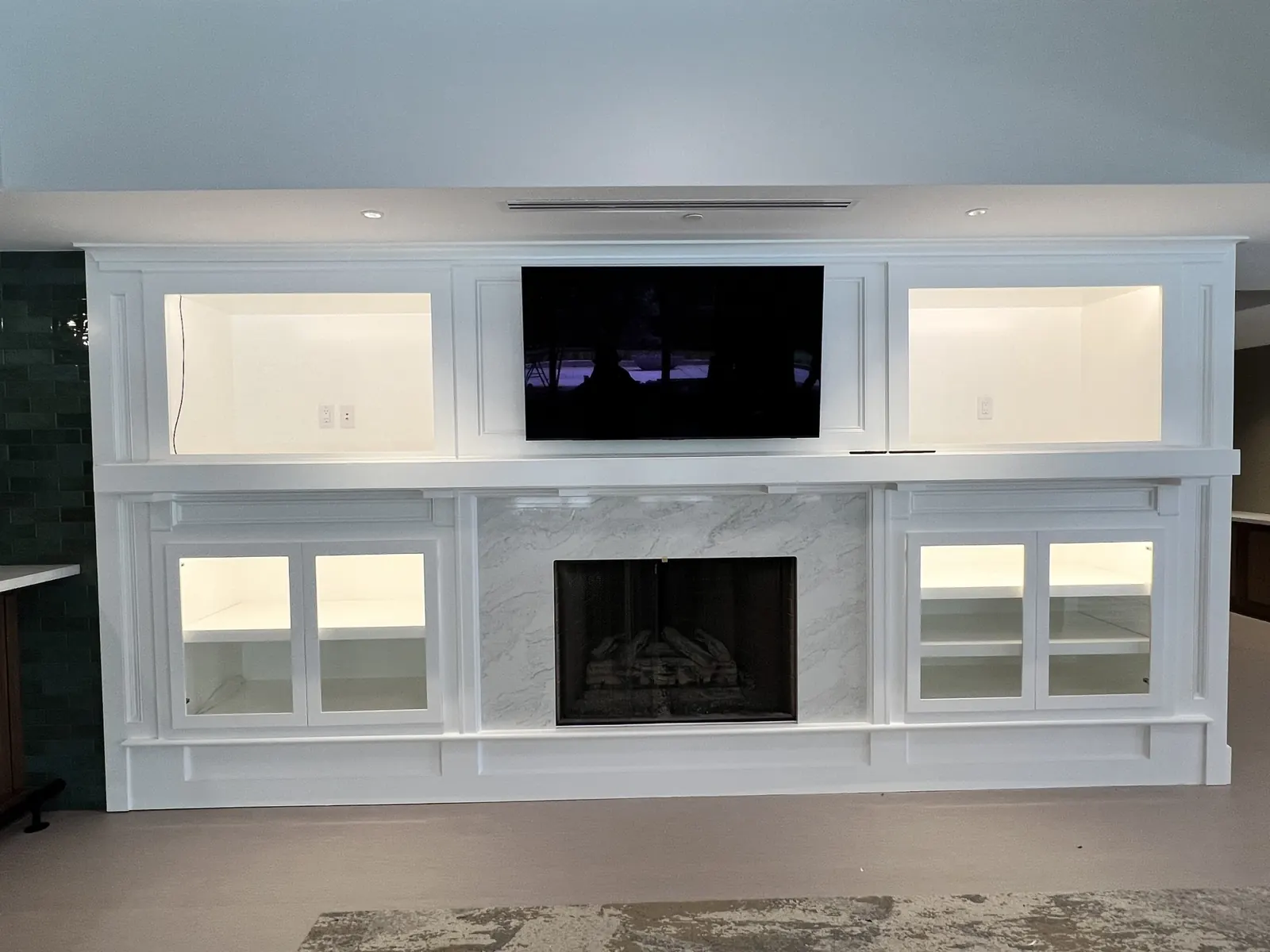 Painted built-ins with lit glass cabinets around a fireplace