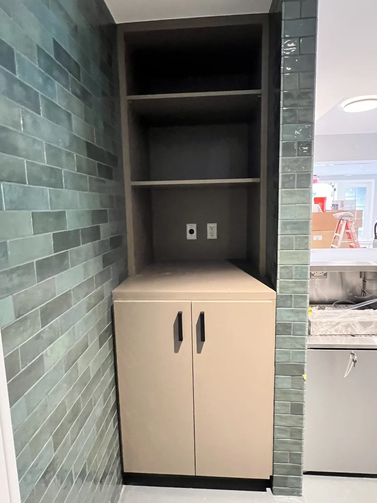 Open shelving cabinet beside a tile wall